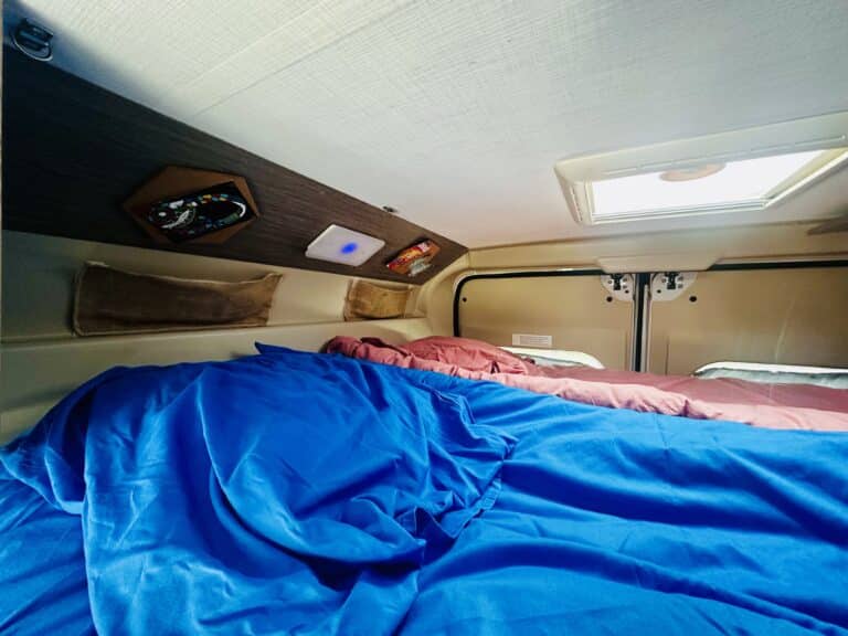 Intérieur de camping-car avec lit et hublot.