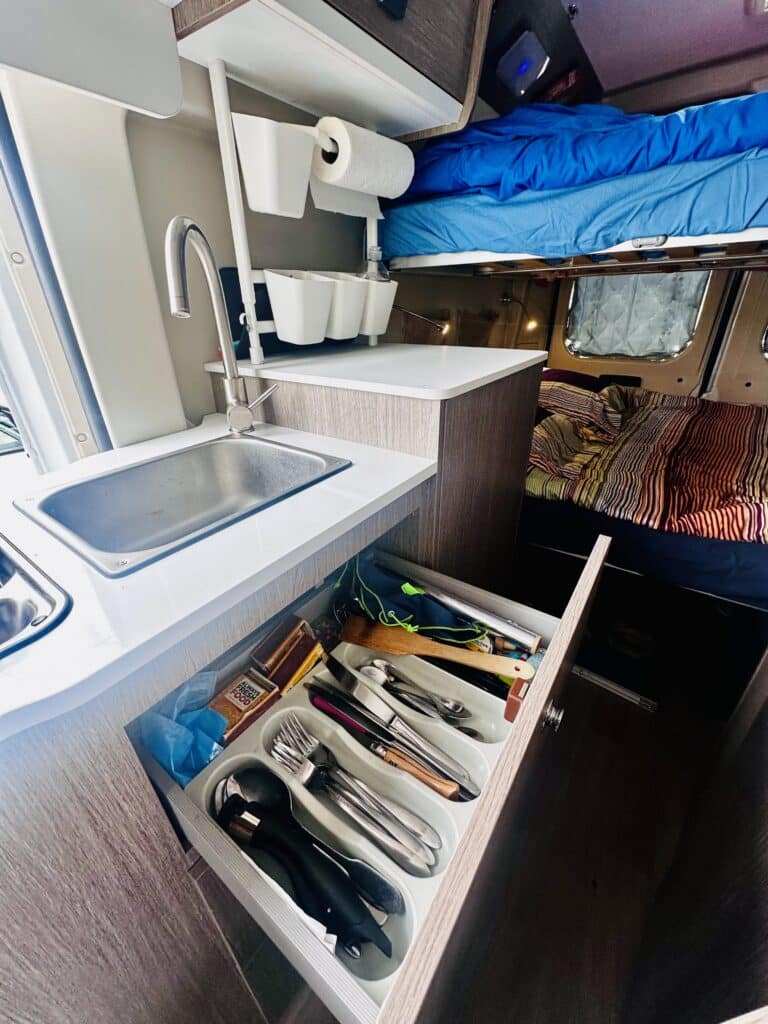 Intérieur de camping-car avec évier et lit.