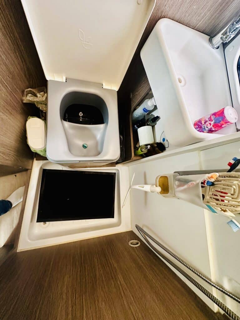 Salle de bain compacte avec lavabo et placard ouverts.