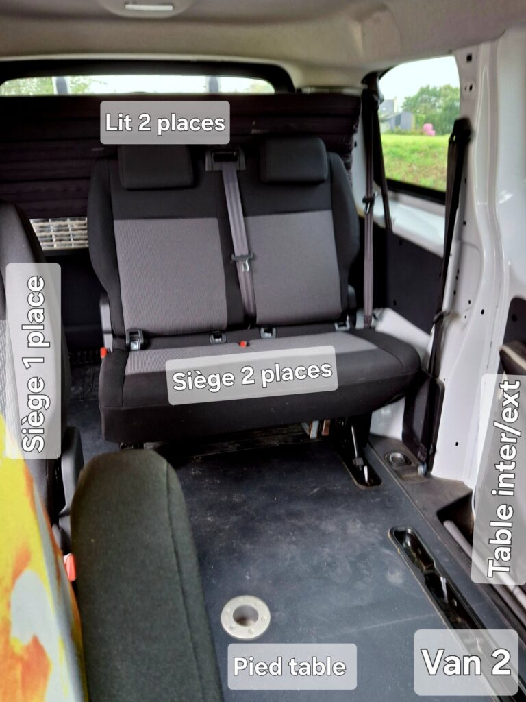 Intérieur d'un van avec sièges et lit.
