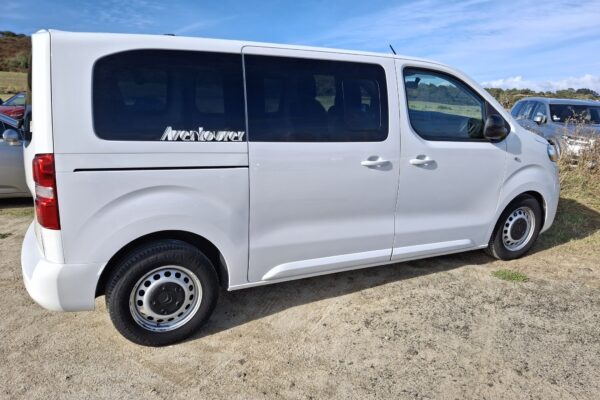 Fourgonnette blanche stationnée sur un chemin.