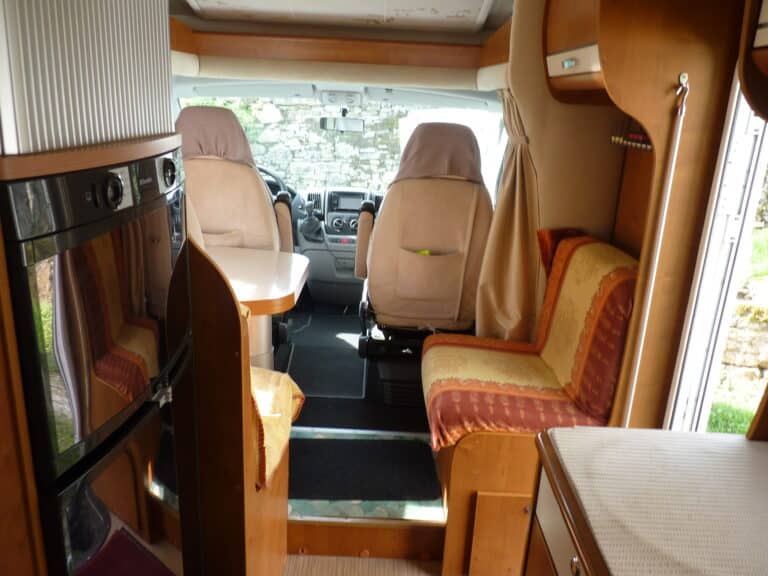 Intérieur de camping-car avec sièges et cuisine.