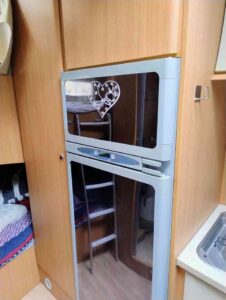 Réfrigérateur encastré dans une caravane, porte avec cœur décoratif.