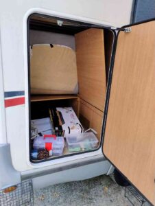 Compartiment de rangement de caravane avec divers articles.