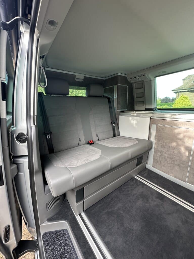 Intérieur d'un van aménagé avec banquette grise.