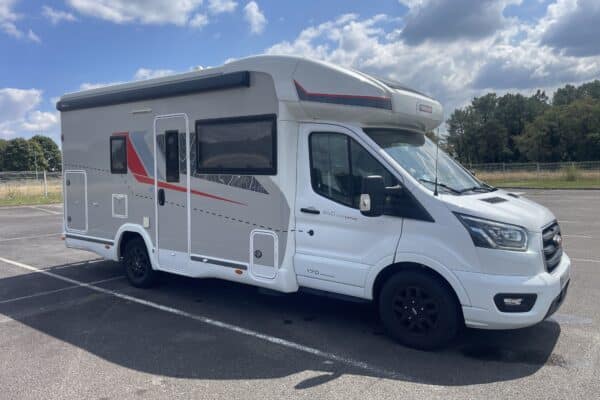 Camping-car blanc stationné sur un parking.