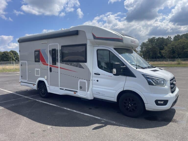 Camping-car blanc stationné sur un parking.
