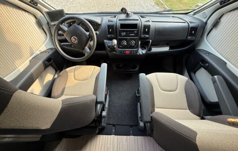 Intérieur de cabine de camping-car avec sièges et volant.