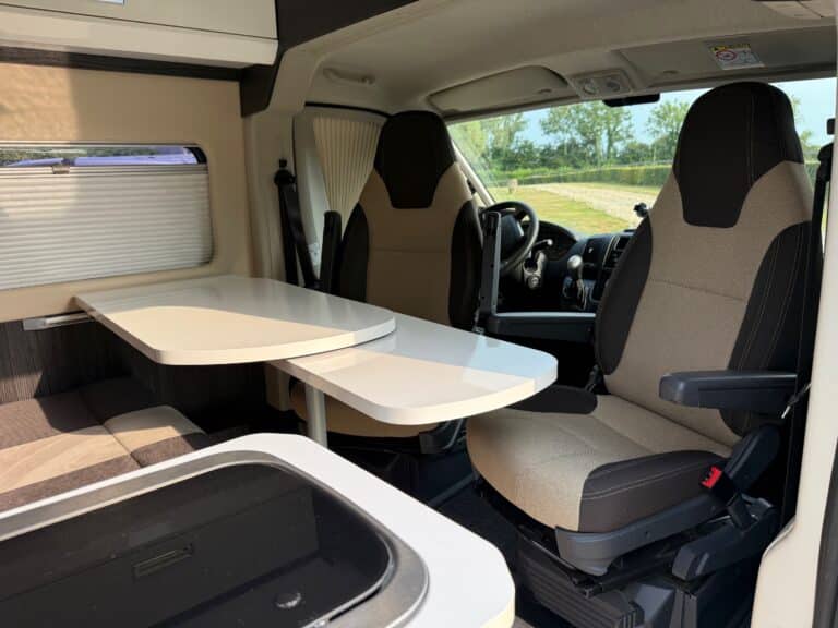 Intérieur de camping-car avec sièges pivotants et table.