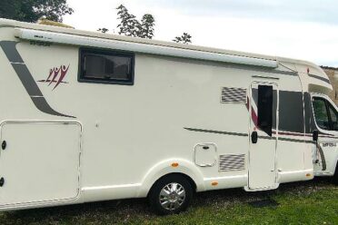 Camping-car blanc garé sur pelouse.