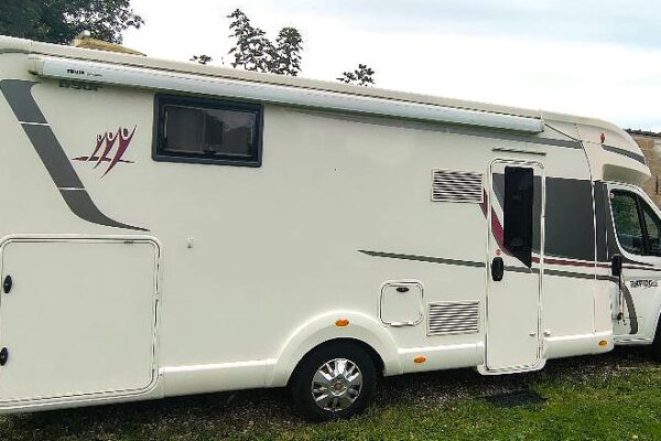 Camping-car blanc garé sur pelouse.