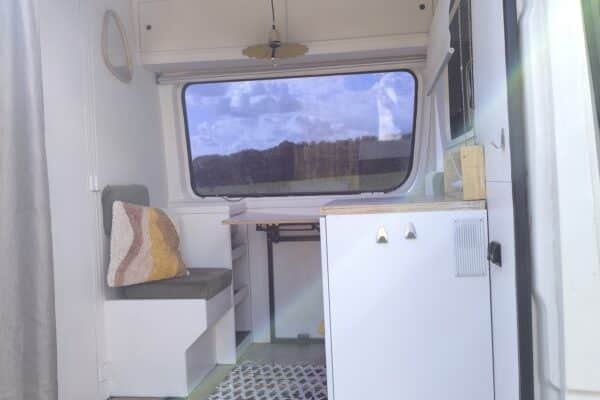 Heller Innenraum eines Campervan mit buntem Teppich.