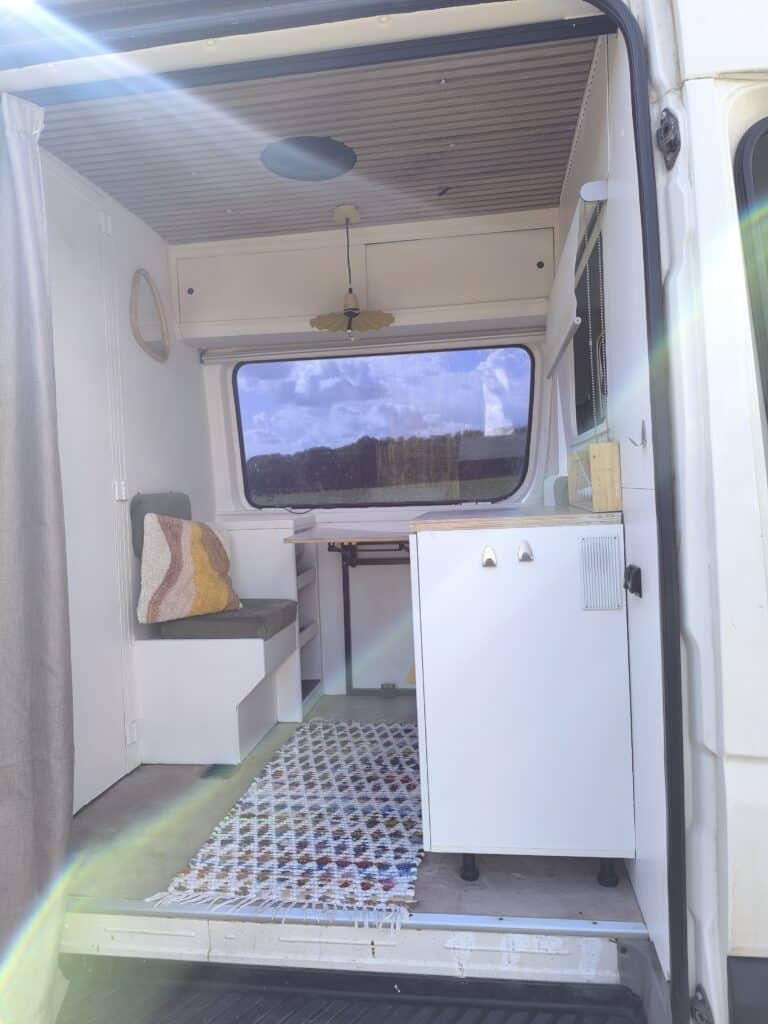 Intérieur lumineux d'un van aménagé avec tapis coloré.