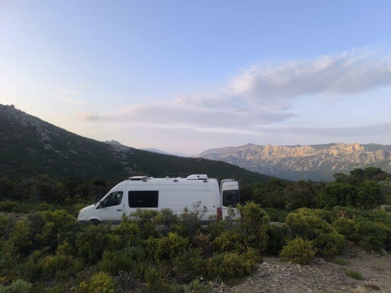 Camion blanc dans paysage montagneux méditerranéen.