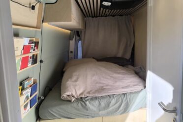 Intérieur de van aménagé avec lit et rangement.