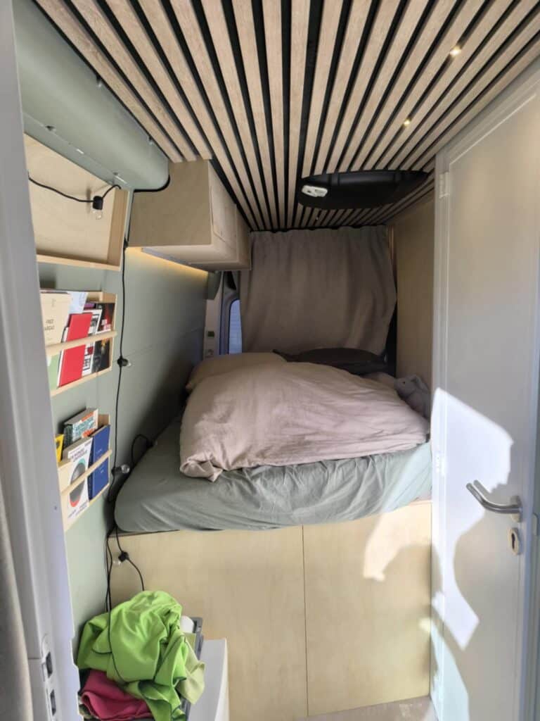 Intérieur de van aménagé avec lit et rangement.