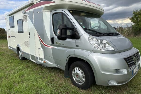 Camping-car garé sur l'herbe sous ciel nuageux.
