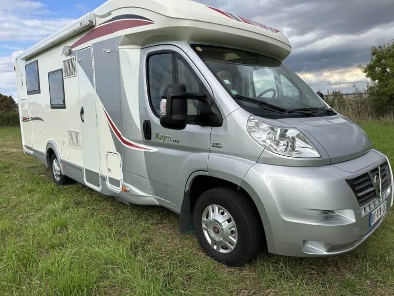 Camping-car garé sur l'herbe sous ciel nuageux.