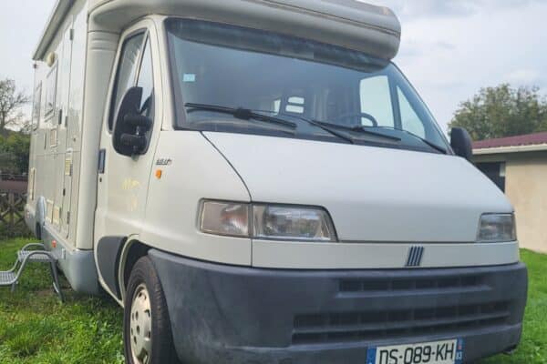 Camping-car garé sur l'herbe, ciel nuageux.