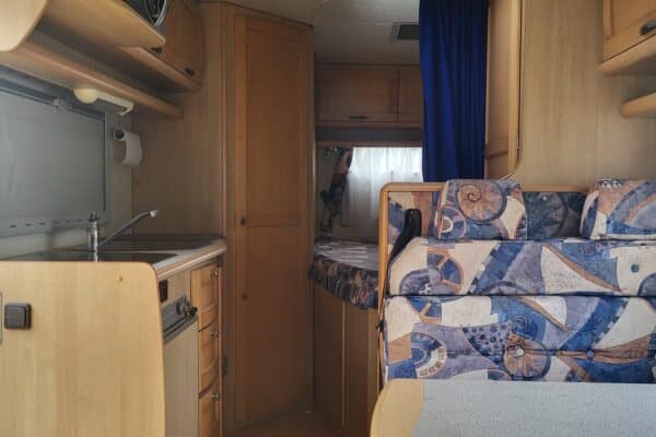 Intérieur d'une caravane avec cuisine et banquette.