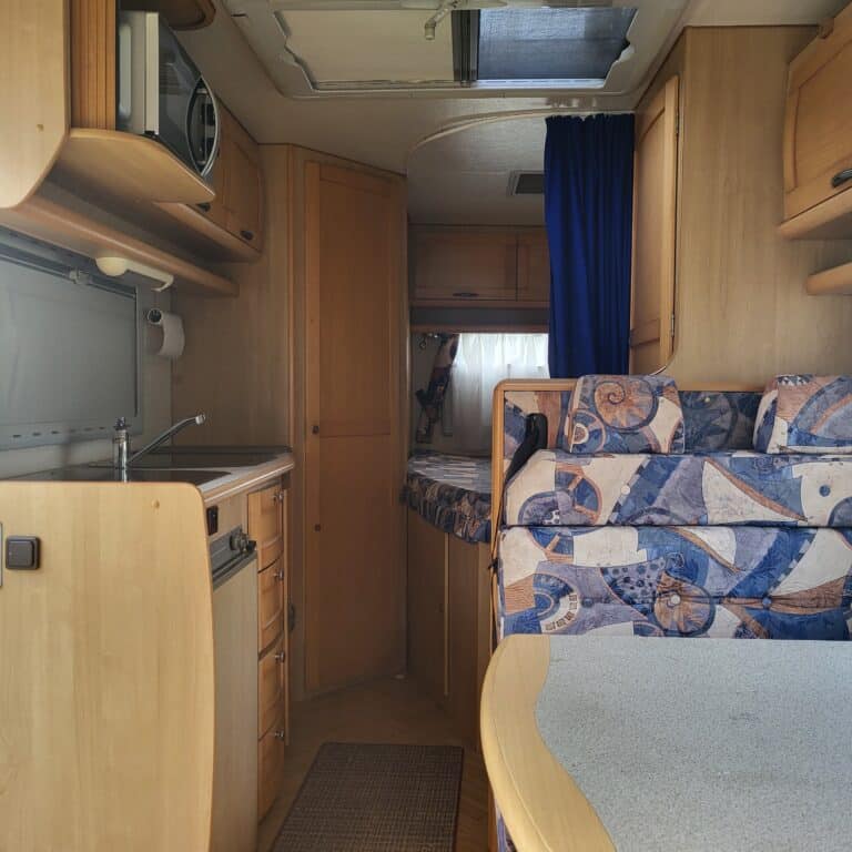 Intérieur d'une caravane avec cuisine et banquette.