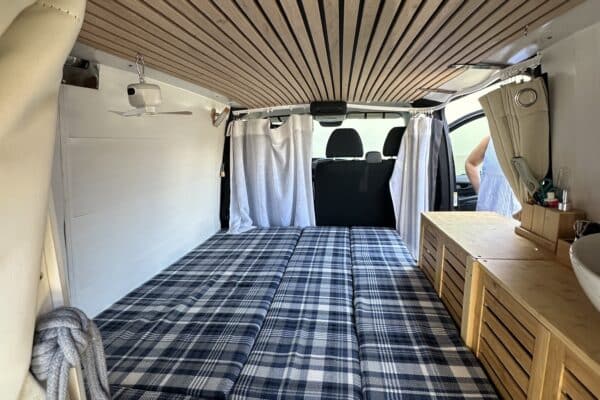 Innenausstattung eines renovierten Campervans mit Bett und Stauraum.