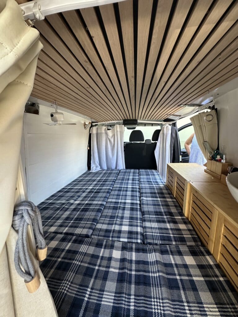 Intérieur de van rénové avec lit et rangement.