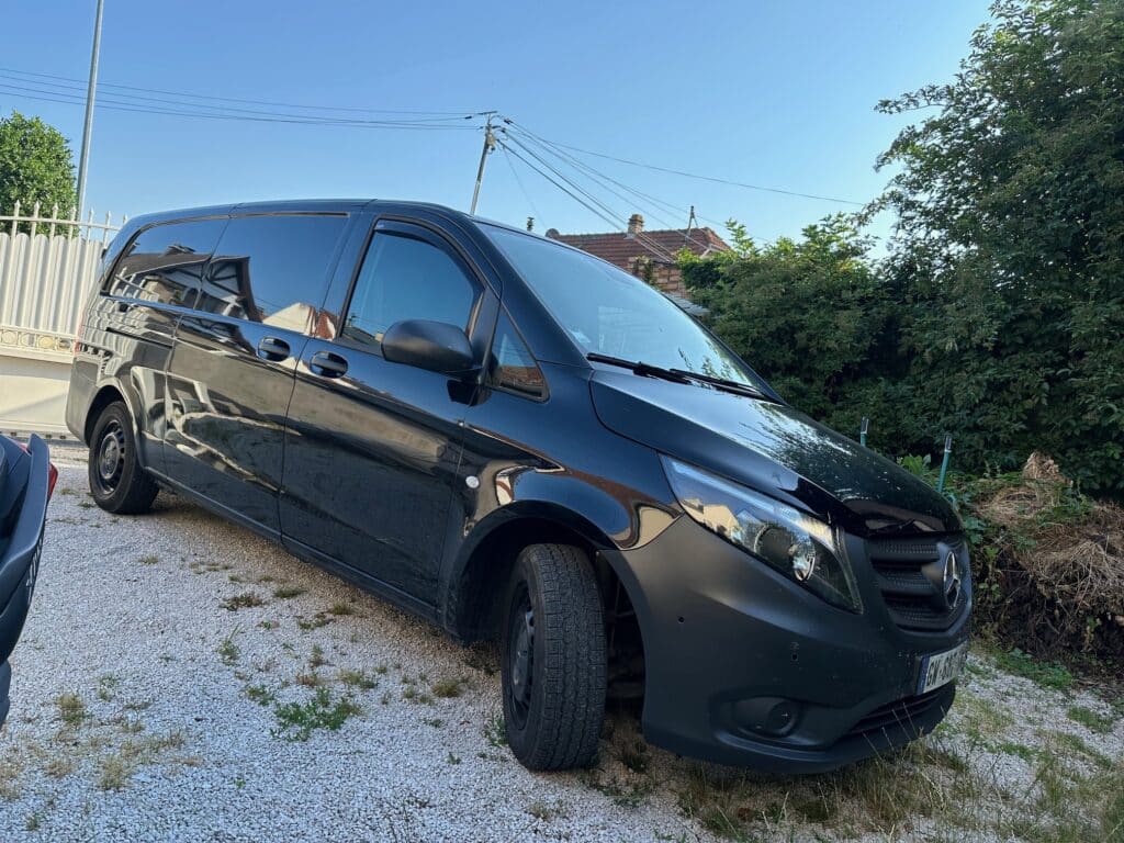 Camionnette noire Mercedes stationnée sur gravier.