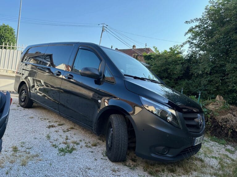 Camionnette noire Mercedes stationnée sur gravier.