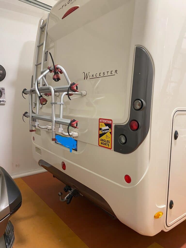 Arrière de camping-car blanc avec porte-vélos.