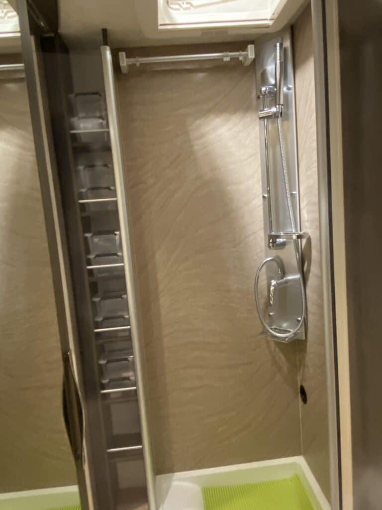 Douche moderne avec rangement intégré et tapis vert.