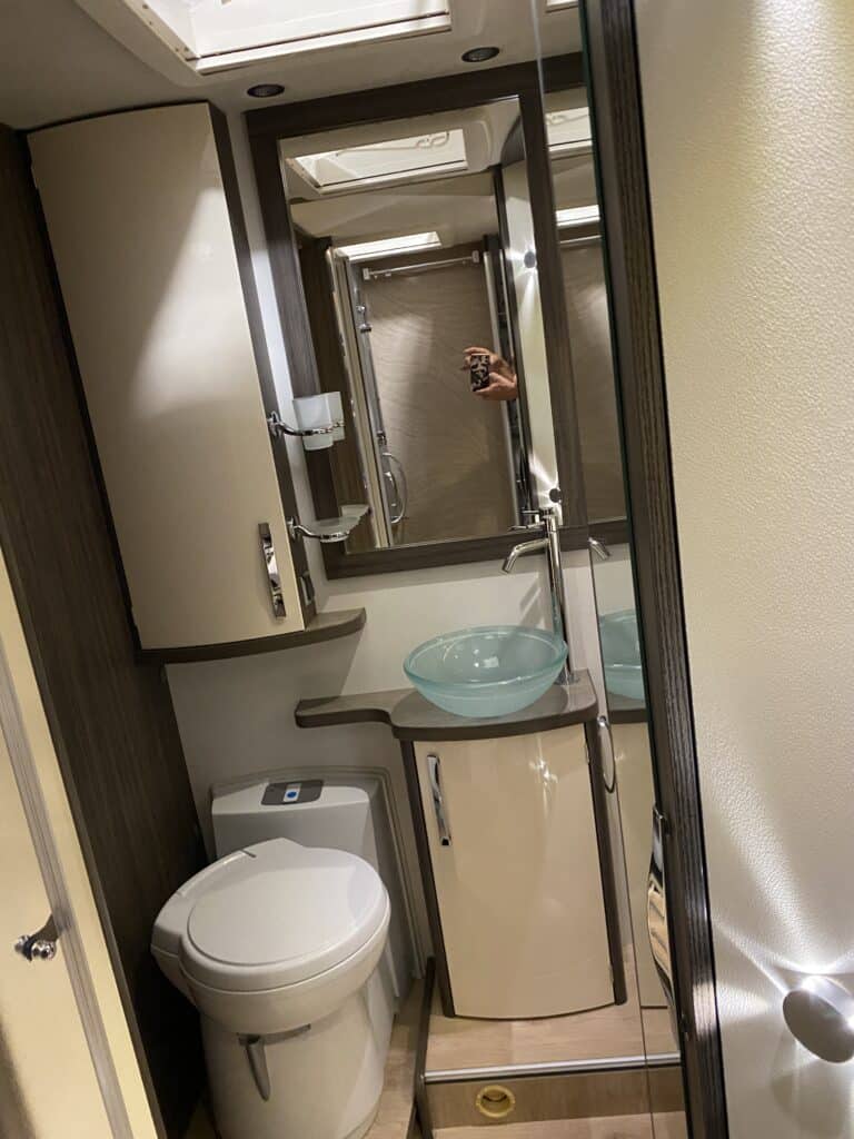 Salle de bain moderne avec lavabo transparent et miroir.