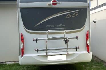 Camping-car stationné dans une cour herbeuse.