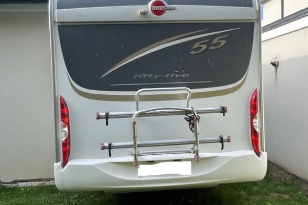 Camping-car stationné dans une cour herbeuse.