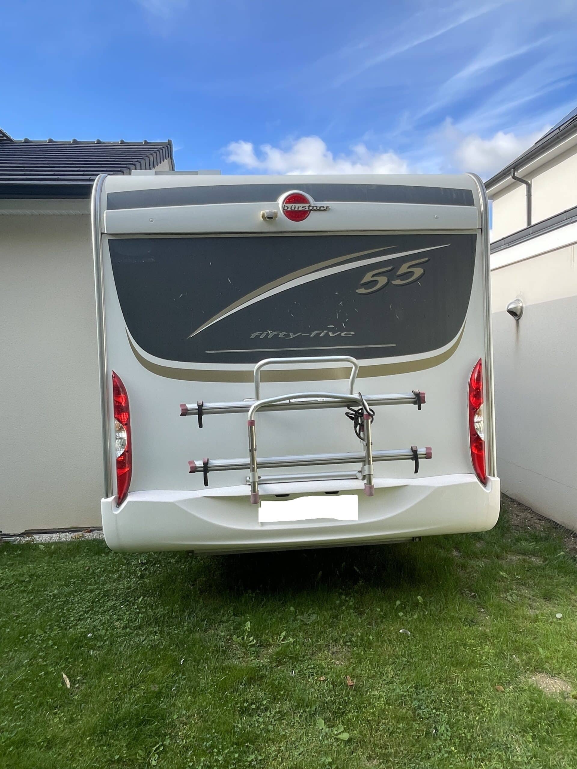 Camping-car stationné dans une cour herbeuse.