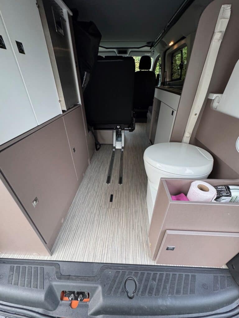 Intérieur d'un van aménagé avec toilettes visibles.