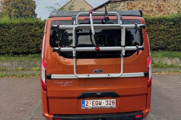Kastenwagen orange mit Fahrradträger auf der Rückseite.