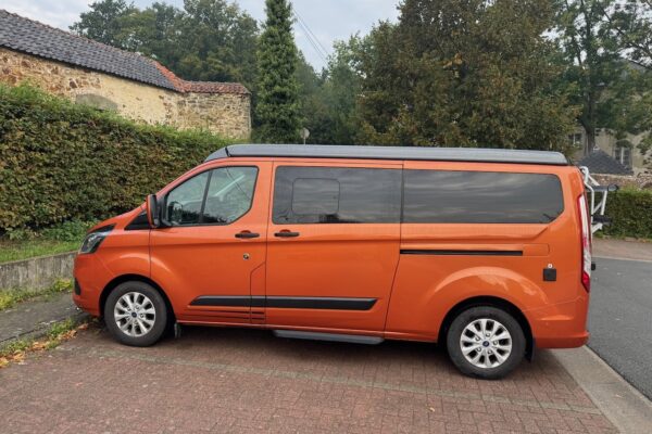 Kastenwagen orange geparkt vor einem alten Gebäude.