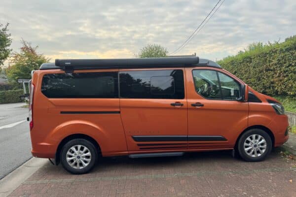 Fourgonnette orange stationnée dans la rue.