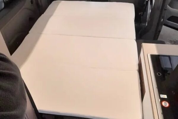 Lit déplié dans un van aménagé moderne.