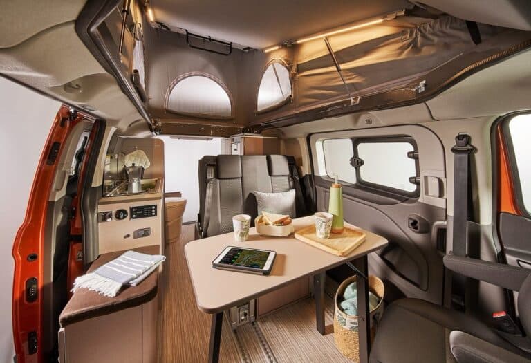 Intérieur d'un van aménagé avec cuisine et table.