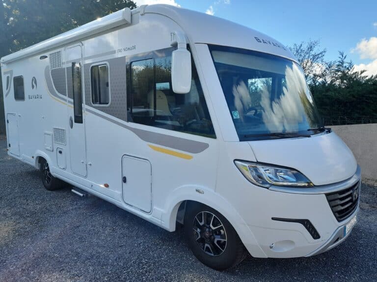 Camping-car blanc stationné sur une allée gravillonnée.