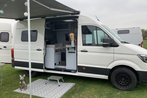 Camping-car blanc aménagé sur terrain vert.