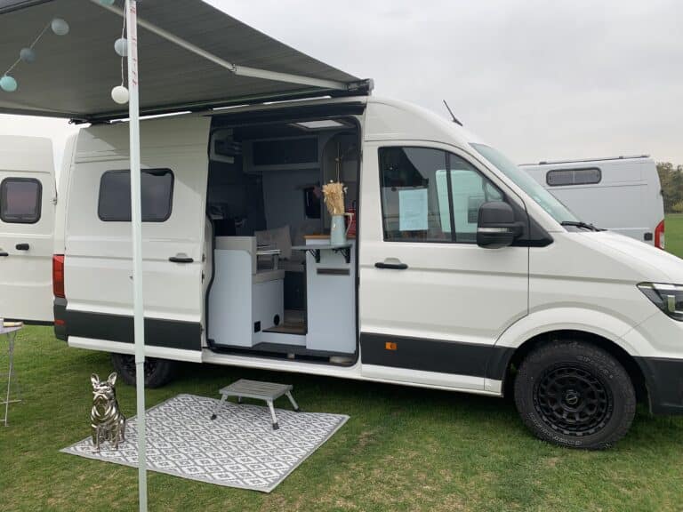 Camping-car blanc aménagé sur terrain vert.