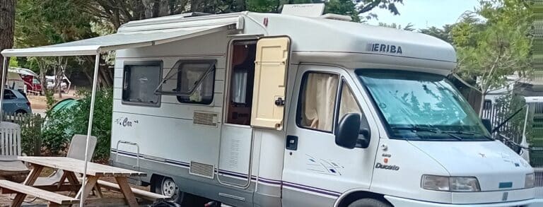 Camping-car avec un auvent déployé sur un camping.