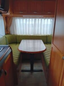 Intérieur de caravane avec banquette et table.