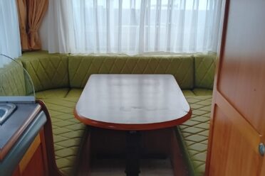 Intérieur de caravane avec banquette et table.