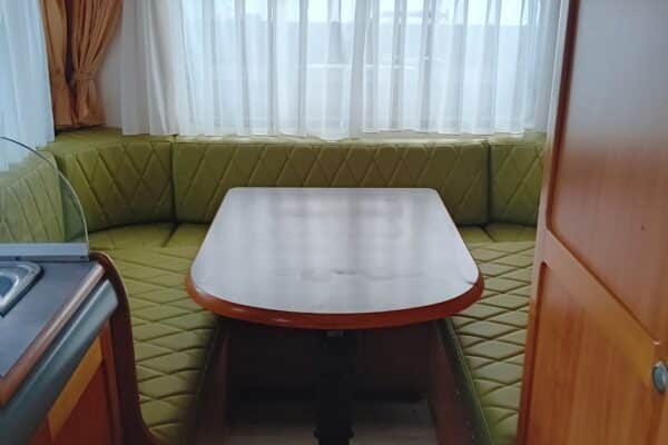 Intérieur de caravane avec banquette et table.