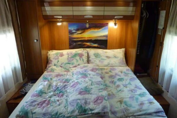 Bequemes Bett in einem Holzzimmer