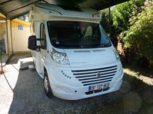 Camping-car blanc garé sous abri.